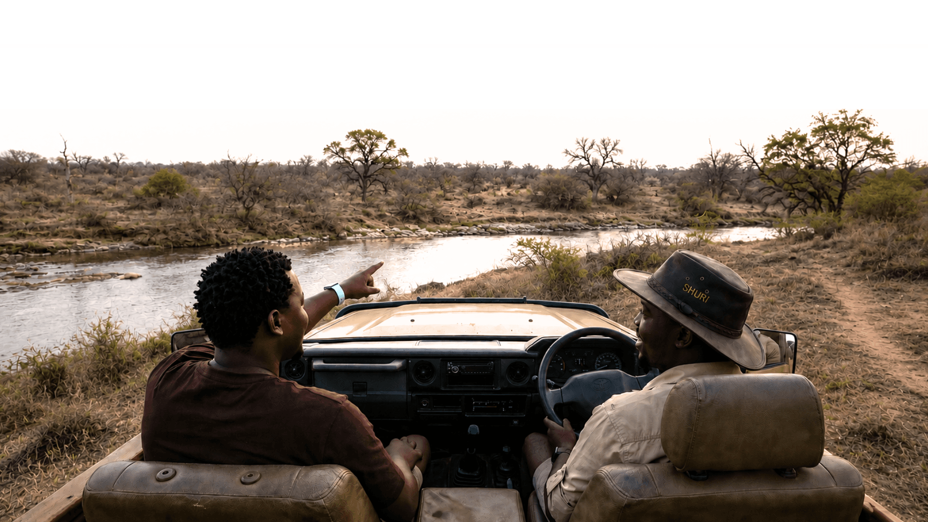 Khaya and Bavu in a game viewer looking out over a river at golden hour