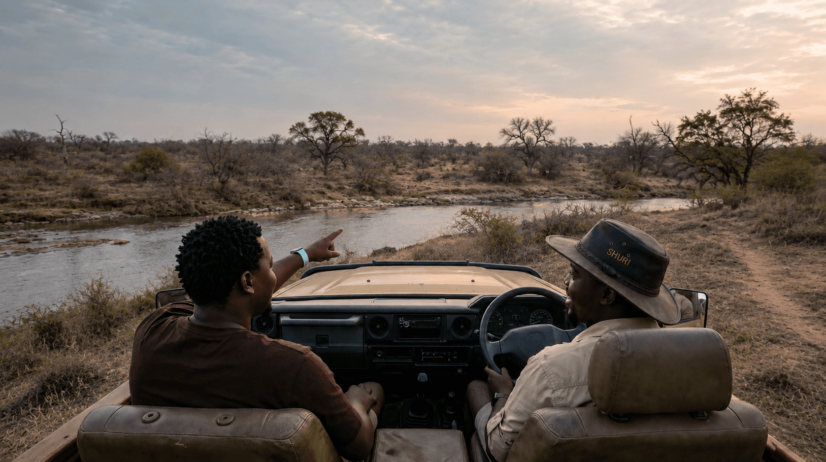 Khaya and Bavu in a game viewer looking out over a river at golden hour